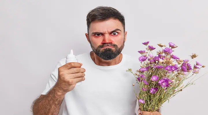 تصویر فردی با علائم آلرژی در کنار گل‌ها