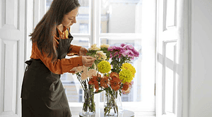 خانمی در حال رسیدگی به گل در گلدان آب