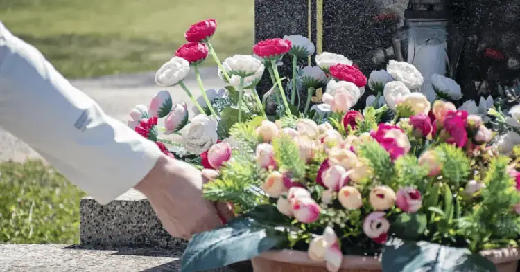 فردی در حال گذاشتن گل روی قبر